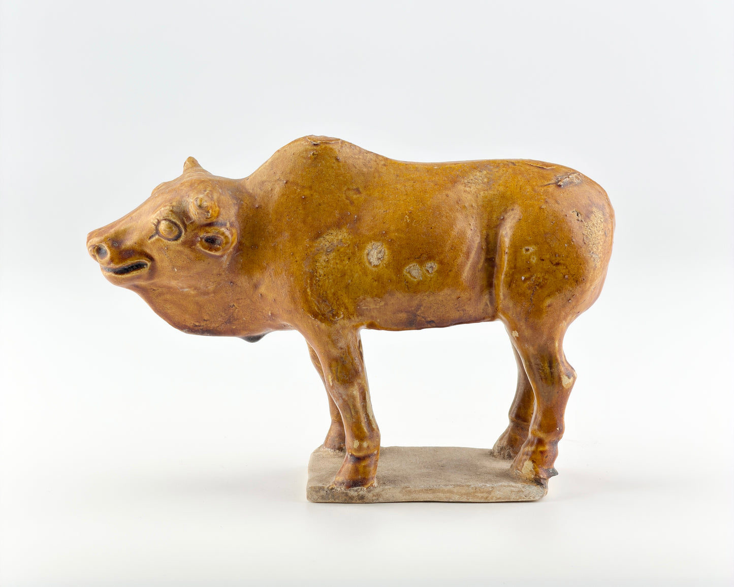 AMBER-GLAZED POTTERY FIGURE OF SACRED BULL, TANG-LIAO DYNASTY (7-12TH CENTURY)