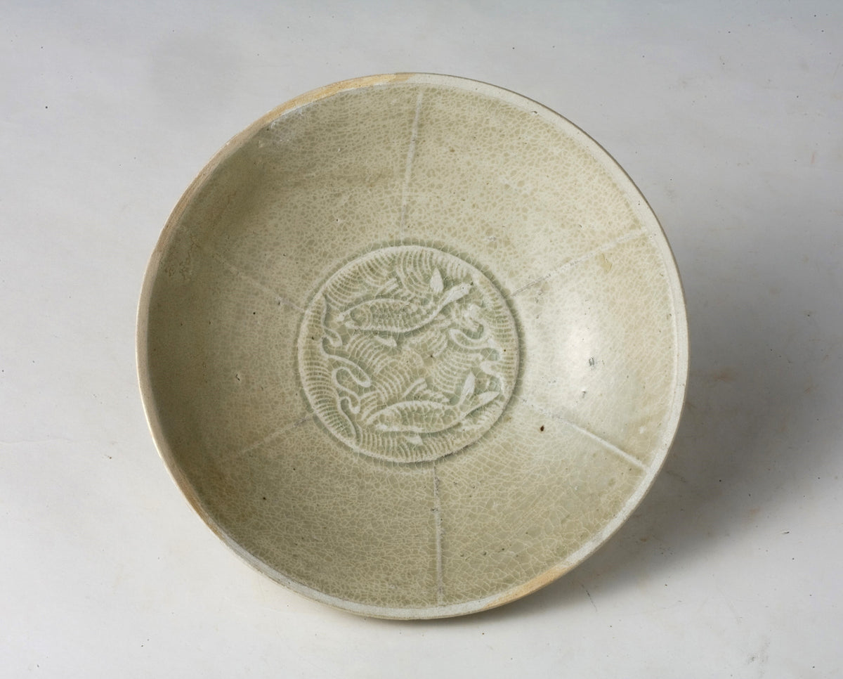 Song Dynasty porcelain bowl with carved twin-fish design, pale blue-white glaze, and low foot.