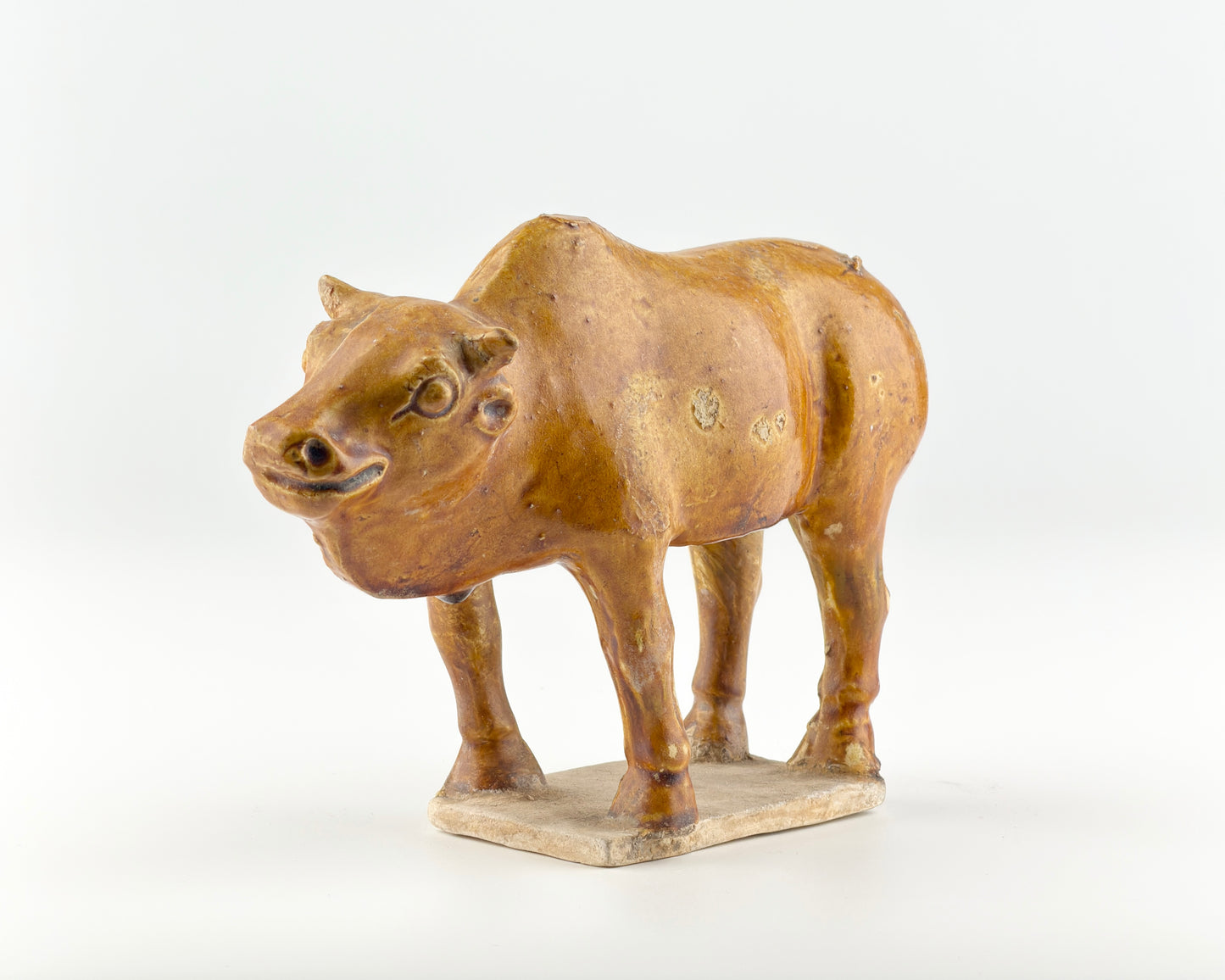 AMBER-GLAZED POTTERY FIGURE OF SACRED BULL, TANG-LIAO DYNASTY (7-12TH CENTURY)