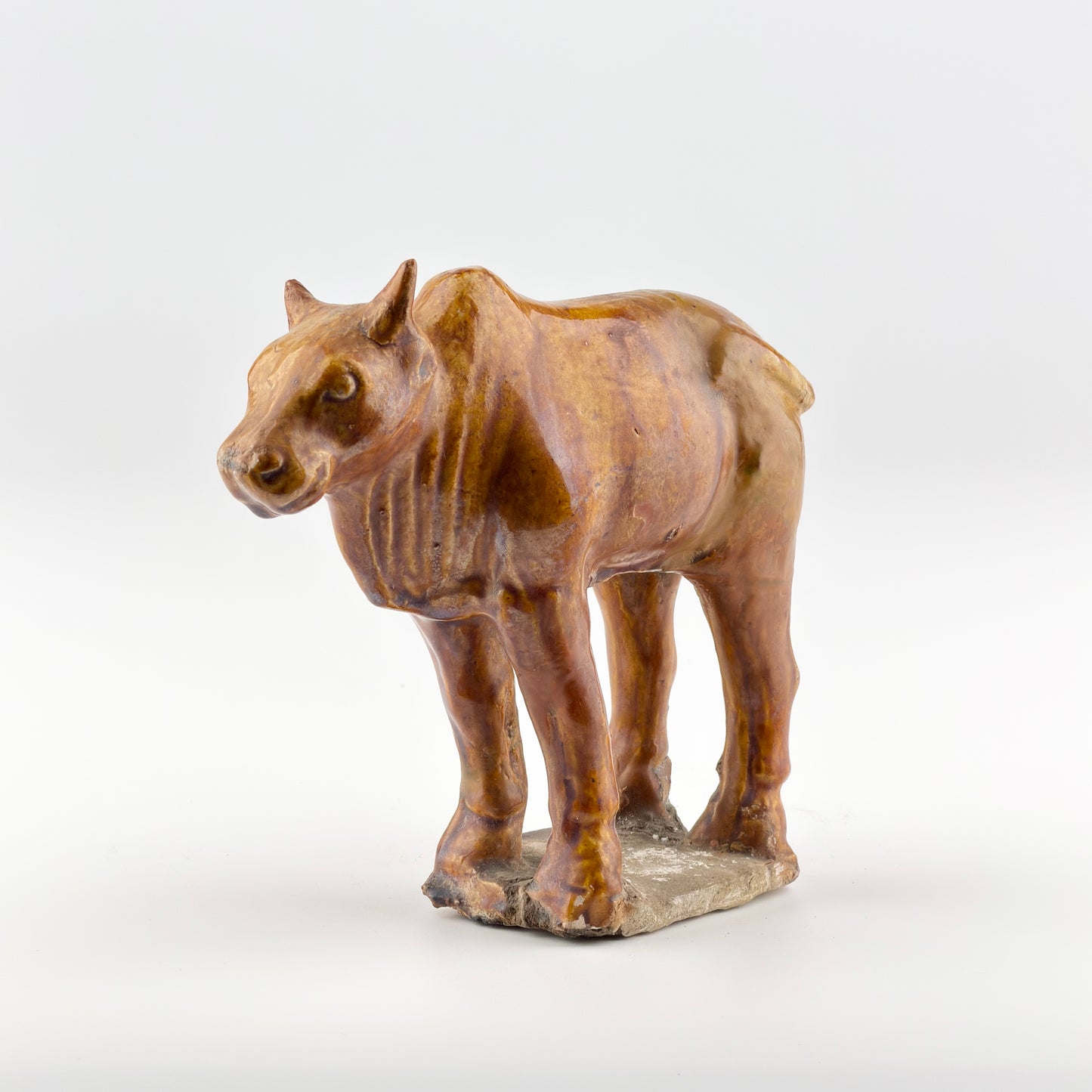 AMBER-GLAZED POTTERY FIGURE OF SACRED BULL, TANG-LIAO DYNASTY (7-12TH CENTURY)