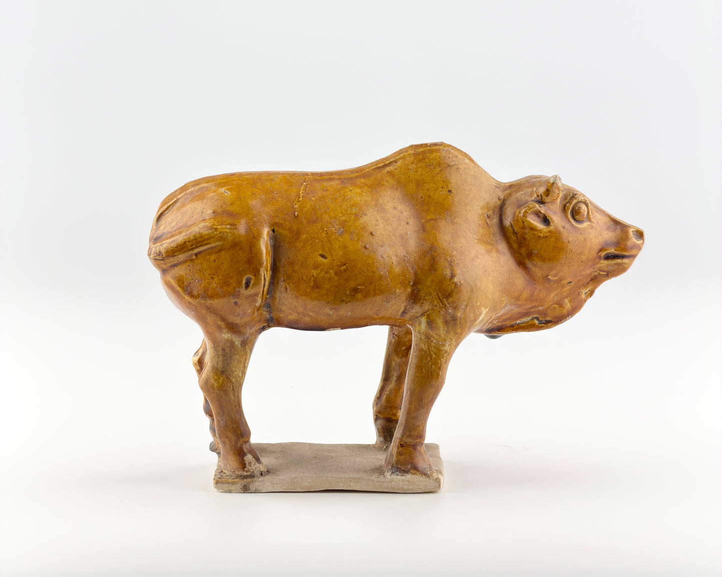 AMBER-GLAZED POTTERY FIGURE OF SACRED BULL, TANG-LIAO DYNASTY (7-12TH CENTURY)