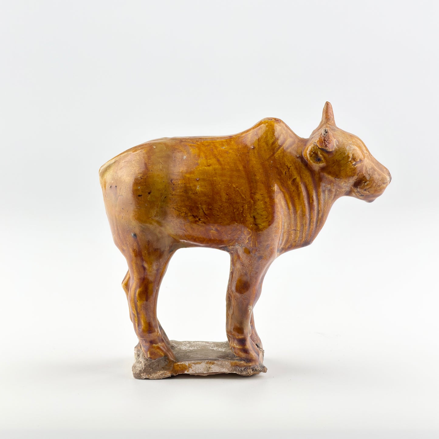 AMBER-GLAZED POTTERY FIGURE OF SACRED BULL, TANG-LIAO DYNASTY (7-12TH CENTURY)