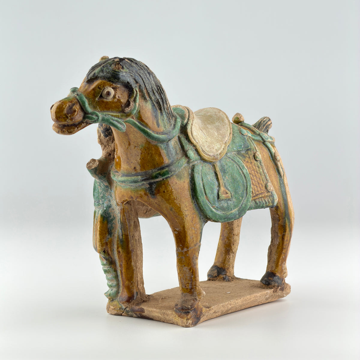 Ming Dynasty pottery horse and rider figures with green and amber glazes, standing on rectangular bases.