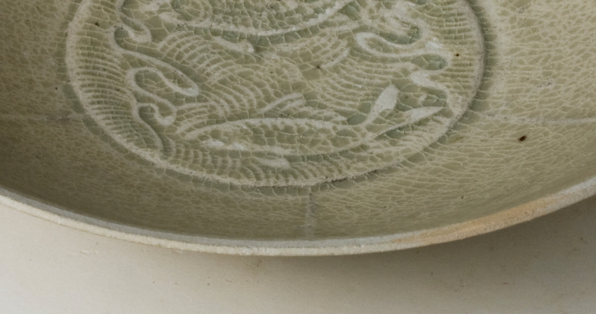 Song Dynasty porcelain bowl with carved twin-fish design, pale blue-white glaze, and low foot.