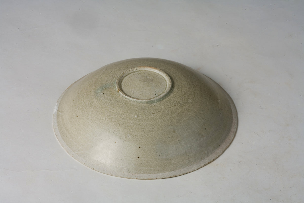Song Dynasty porcelain bowl with carved twin-fish design, pale blue-white glaze, and low foot.