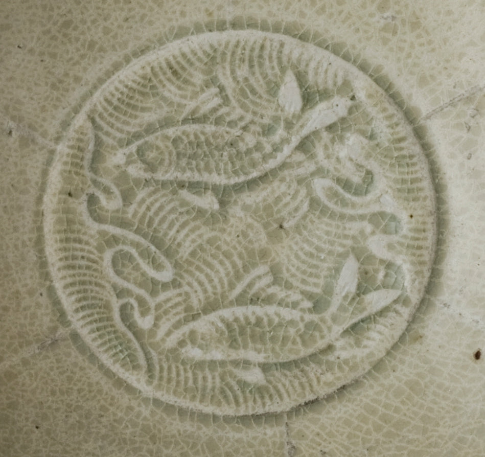 Song Dynasty porcelain bowl with carved twin-fish design, pale blue-white glaze, and low foot.