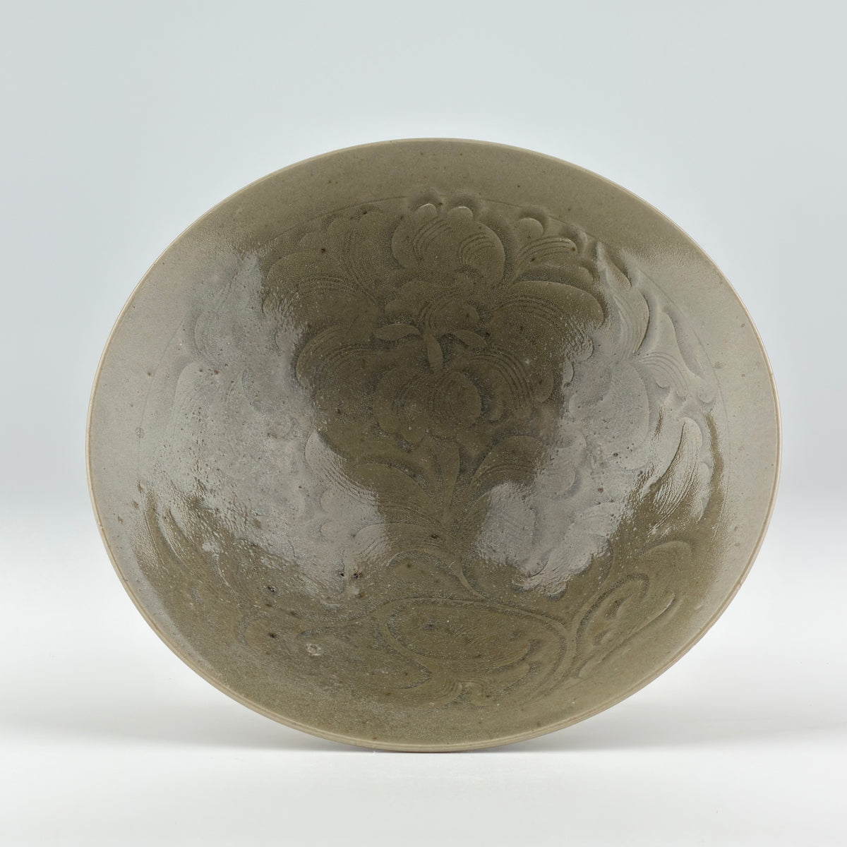 Song Dynasty Yaozhou celadon bowl with carved peony scroll, olive-grey glaze, flared sides, and vertical fluting.