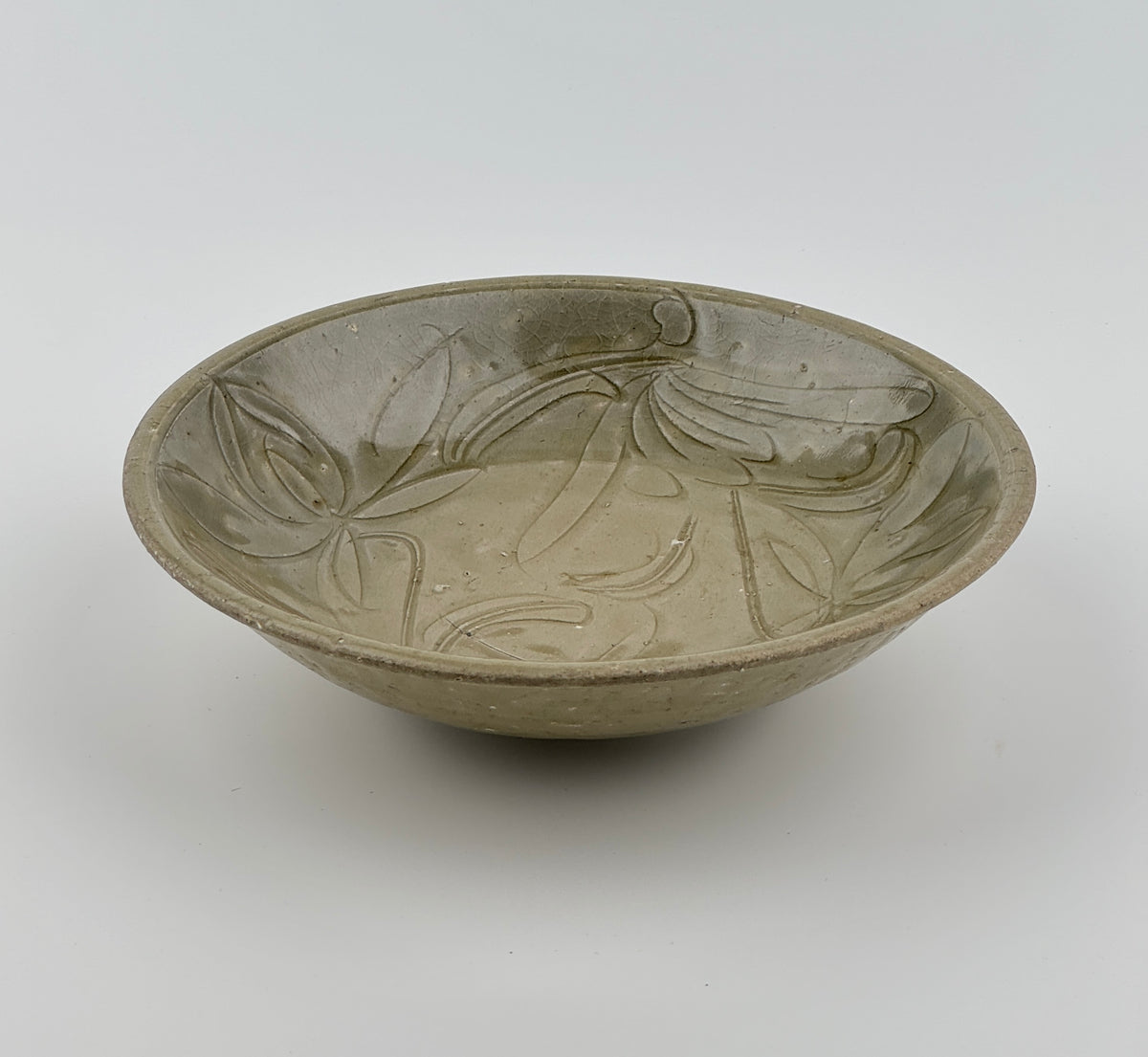 Song Dynasty celadon bowl with incised lotus flower and leaf patterns, soft grayish-green glaze, and fine surface crackling.