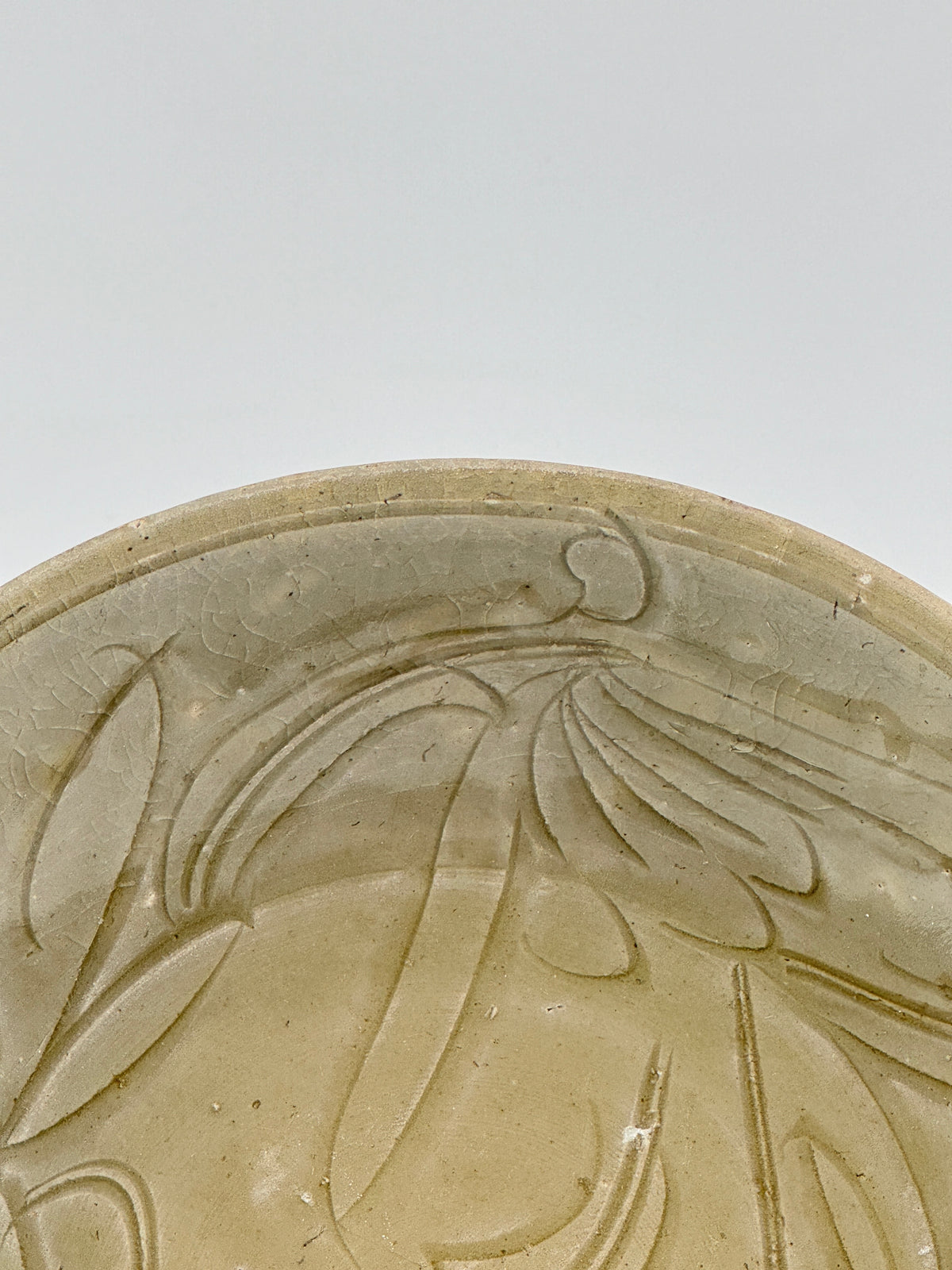 Song Dynasty celadon bowl with incised lotus flower and leaf patterns, soft grayish-green glaze, and fine surface crackling.