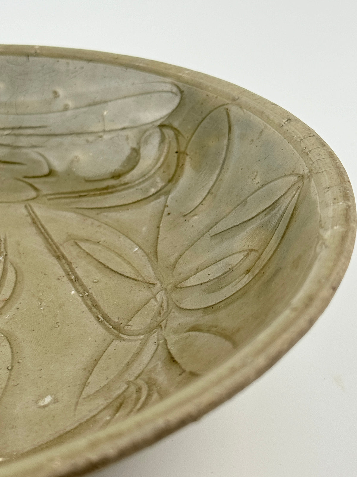 Song Dynasty celadon bowl with incised lotus flower and leaf patterns, soft grayish-green glaze, and fine surface crackling.