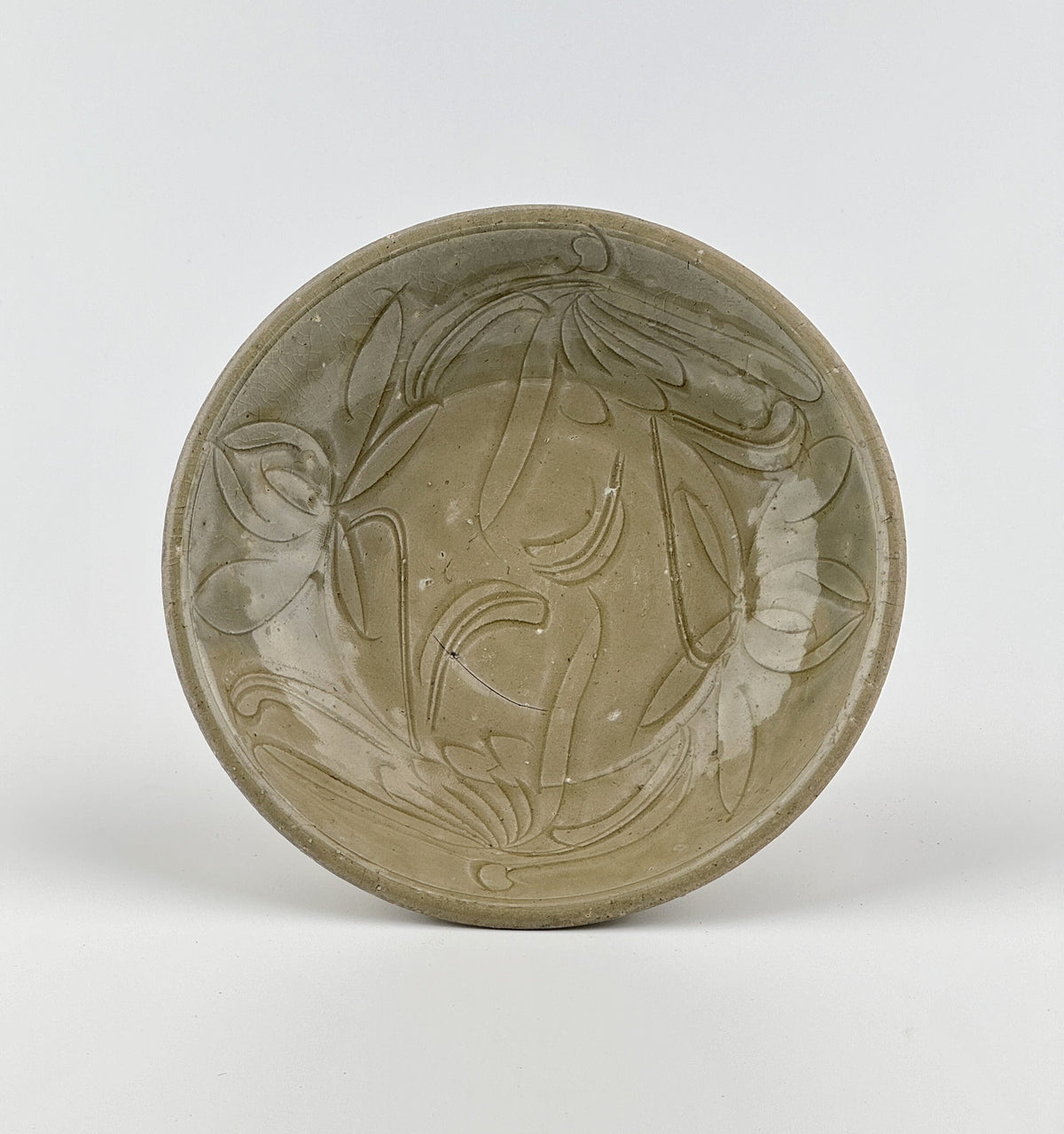 Song Dynasty celadon bowl with incised lotus flower and leaf patterns, soft grayish-green glaze, and fine surface crackling.