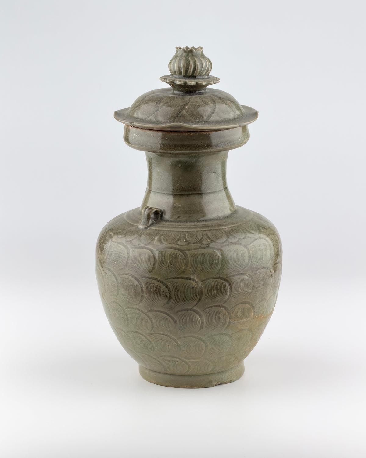 Song Dynasty celadon jar with carved lotus petal design, domed lid, and olive-green glaze.