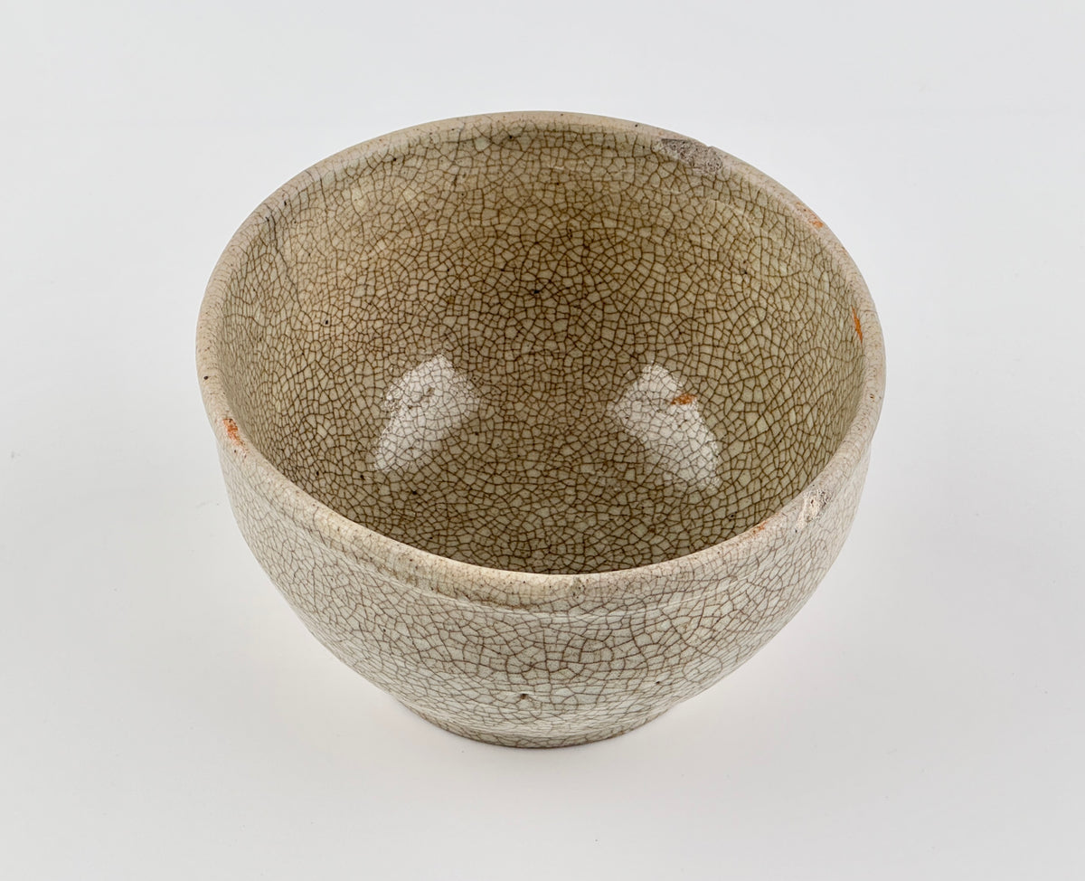 Chinese crackle-glazed ceramic bowl with rounded form, pale grey-yellow glaze, and brown crackle network, Qing or Song Dynasty.
