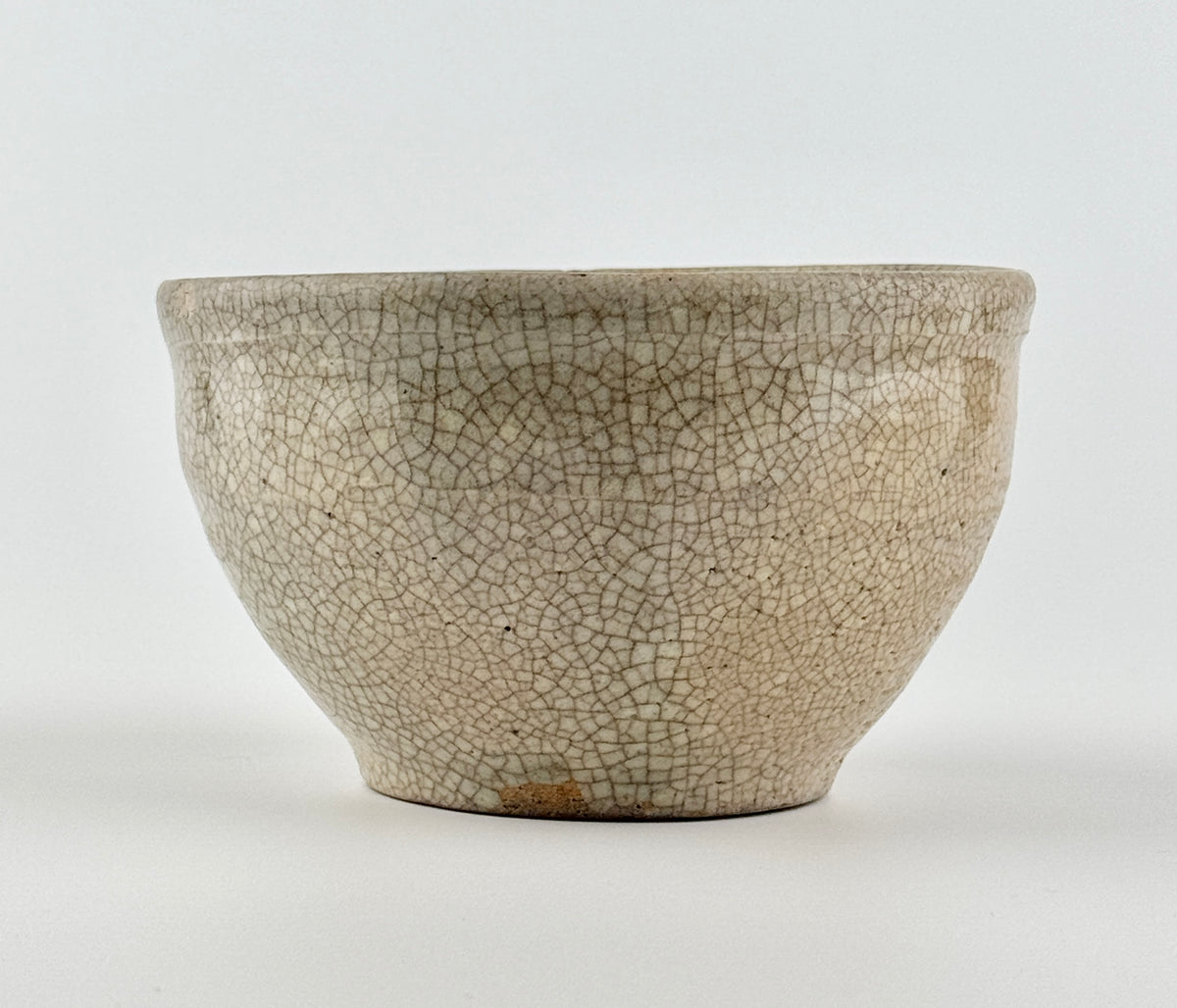 Chinese crackle-glazed ceramic bowl with rounded form, pale grey-yellow glaze, and brown crackle network, Qing or Song Dynasty.