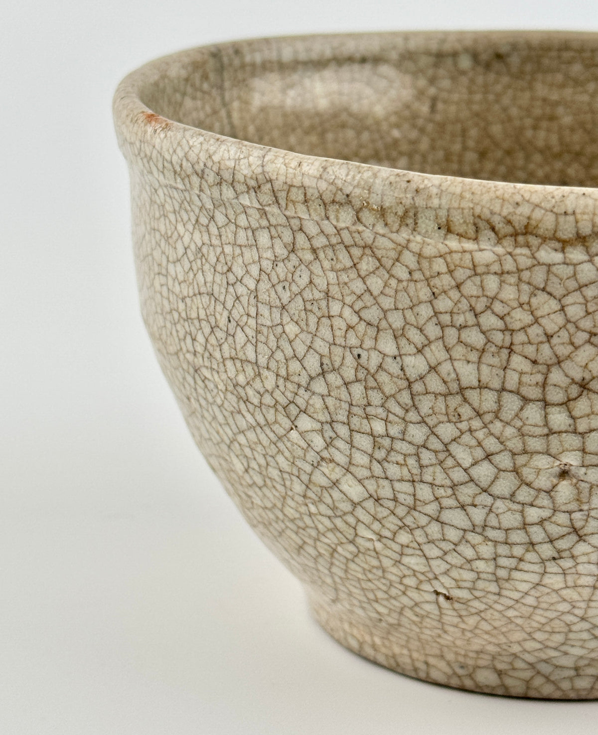 Chinese crackle-glazed ceramic bowl with rounded form, pale grey-yellow glaze, and brown crackle network, Qing or Song Dynasty.