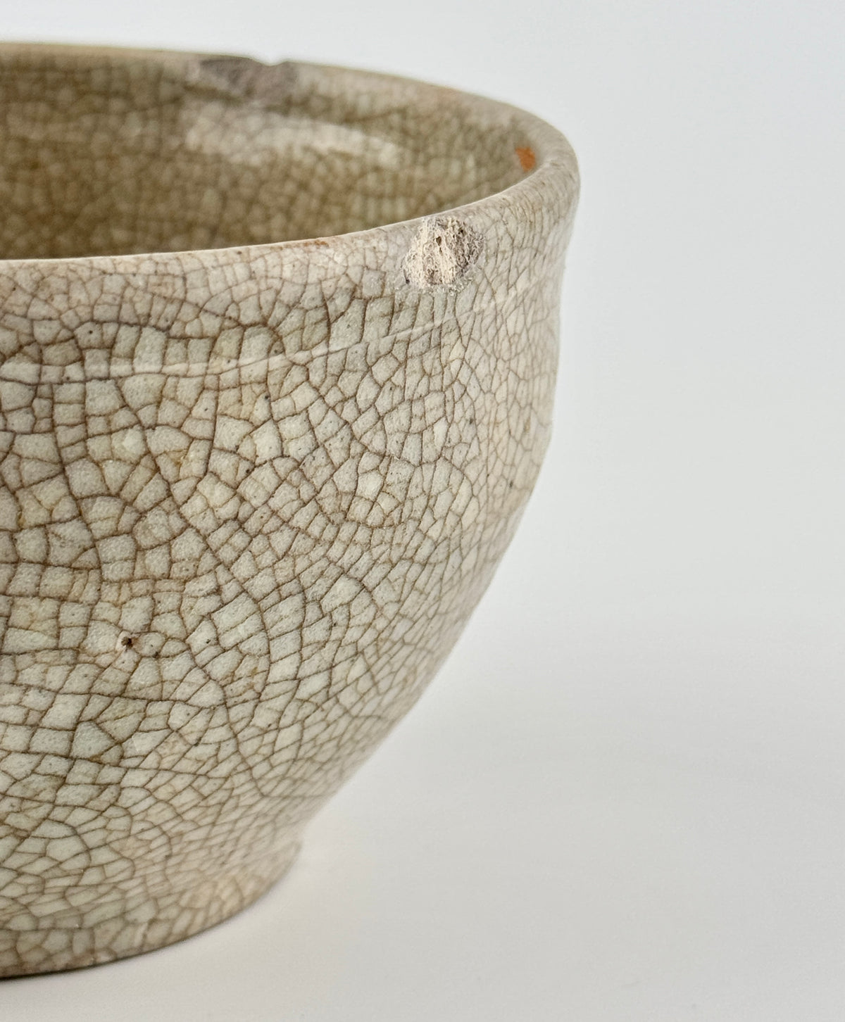 Chinese crackle-glazed ceramic bowl with rounded form, pale grey-yellow glaze, and brown crackle network, Qing or Song Dynasty.
