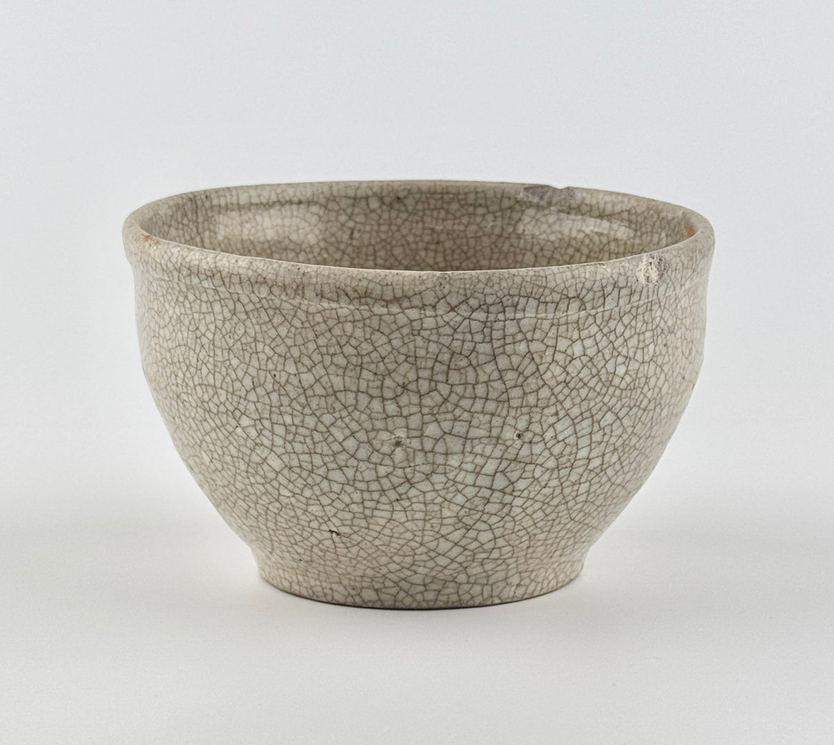 Chinese crackle-glazed ceramic bowl with rounded form, pale grey-yellow glaze, and brown crackle network, Qing or Song Dynasty.