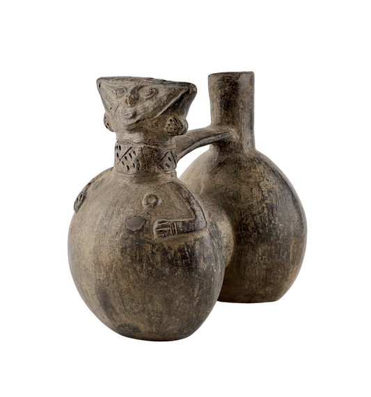 Pre-Columbian Peruvian anthropomorphic double-spouted earthenware vessel with geometric carvings, bridge handle, and unglazed clay surface.