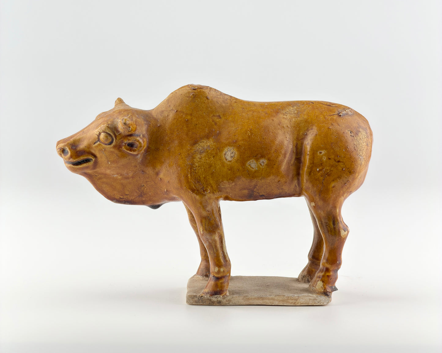 AMBER-GLAZED POTTERY FIGURE OF SACRED BULL, TANG-LIAO DYNASTY (7-12TH CENTURY)