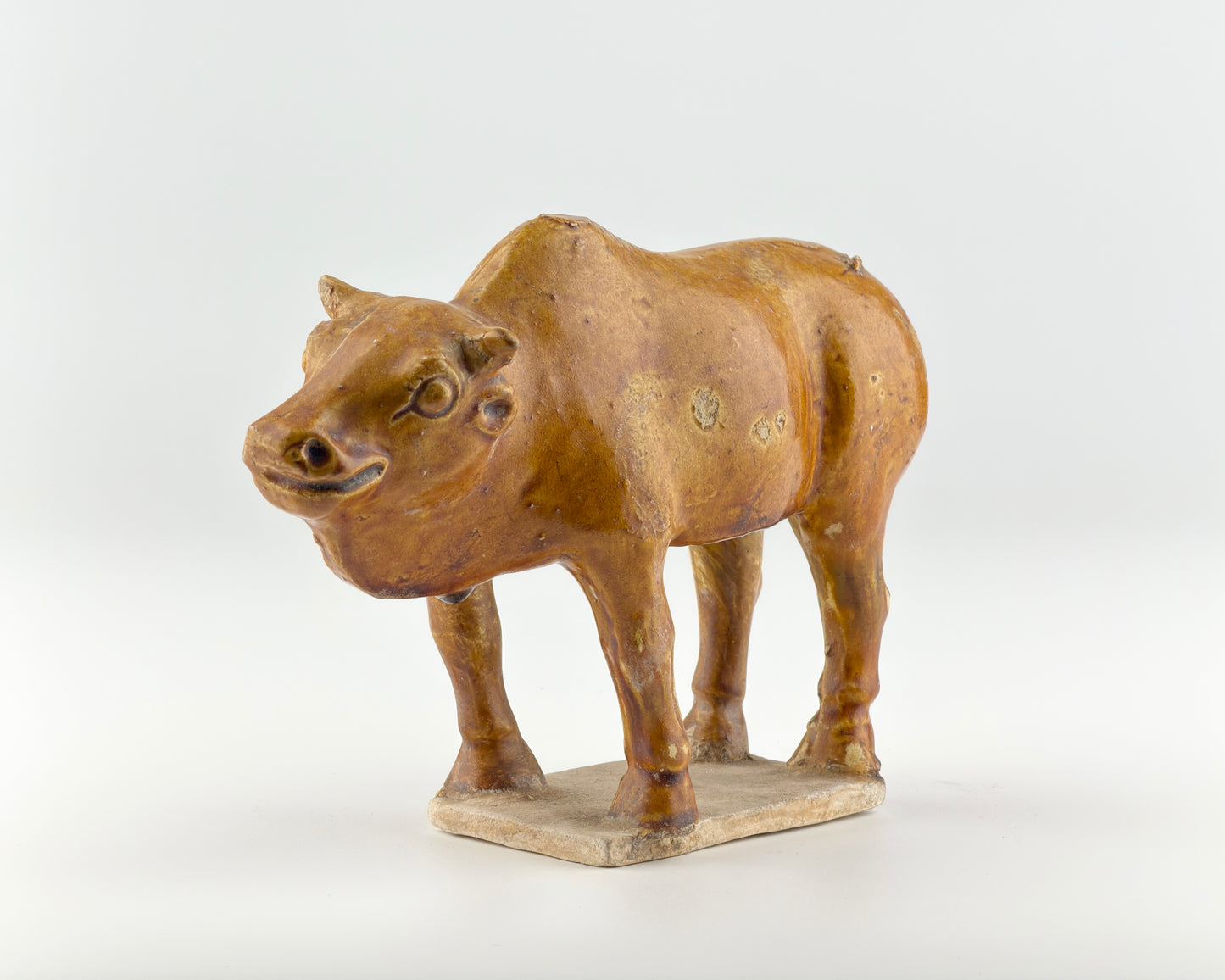 AMBER-GLAZED POTTERY FIGURE OF SACRED BULL, TANG-LIAO DYNASTY (7-12TH CENTURY)