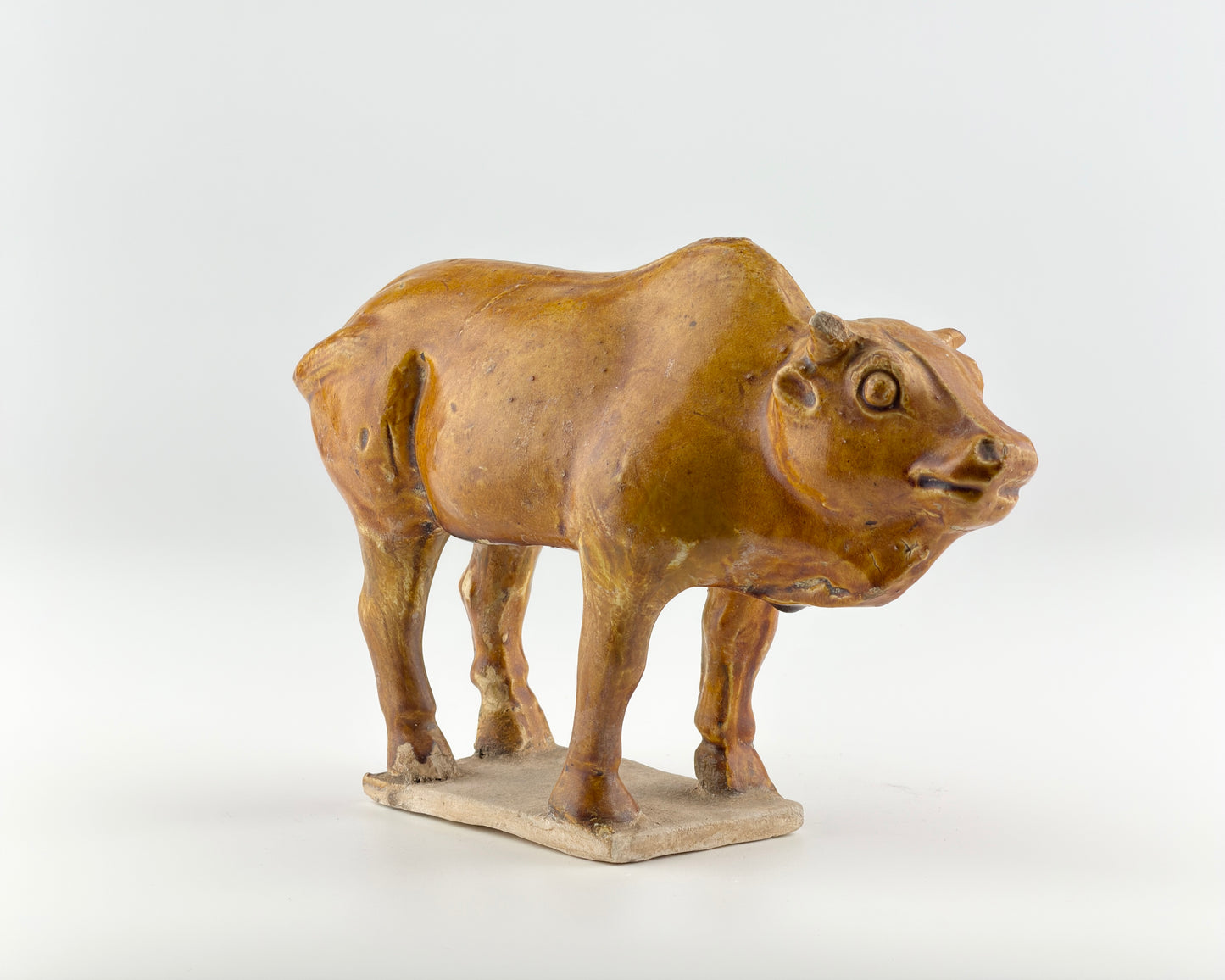 AMBER-GLAZED POTTERY FIGURE OF SACRED BULL, TANG-LIAO DYNASTY (7-12TH CENTURY)