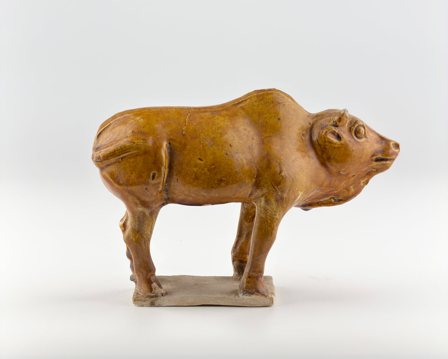 AMBER-GLAZED POTTERY FIGURE OF SACRED BULL, TANG-LIAO DYNASTY (7-12TH CENTURY)