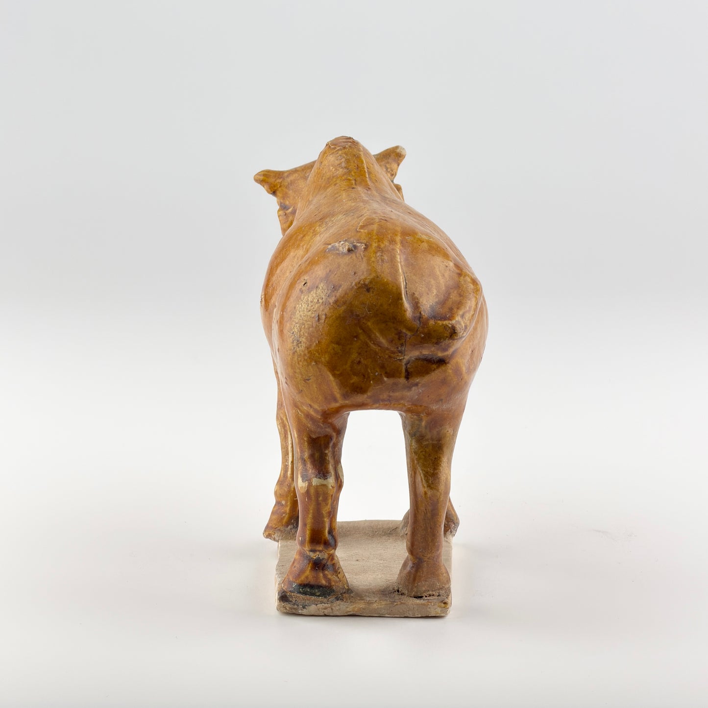 AMBER-GLAZED POTTERY FIGURE OF SACRED BULL, TANG-LIAO DYNASTY (7-12TH CENTURY)