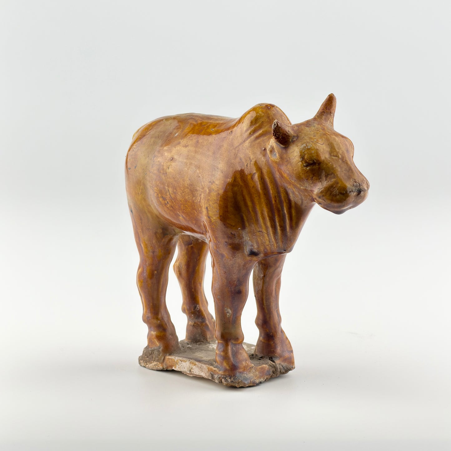 AMBER-GLAZED POTTERY FIGURE OF SACRED BULL, TANG-LIAO DYNASTY (7-12TH CENTURY)