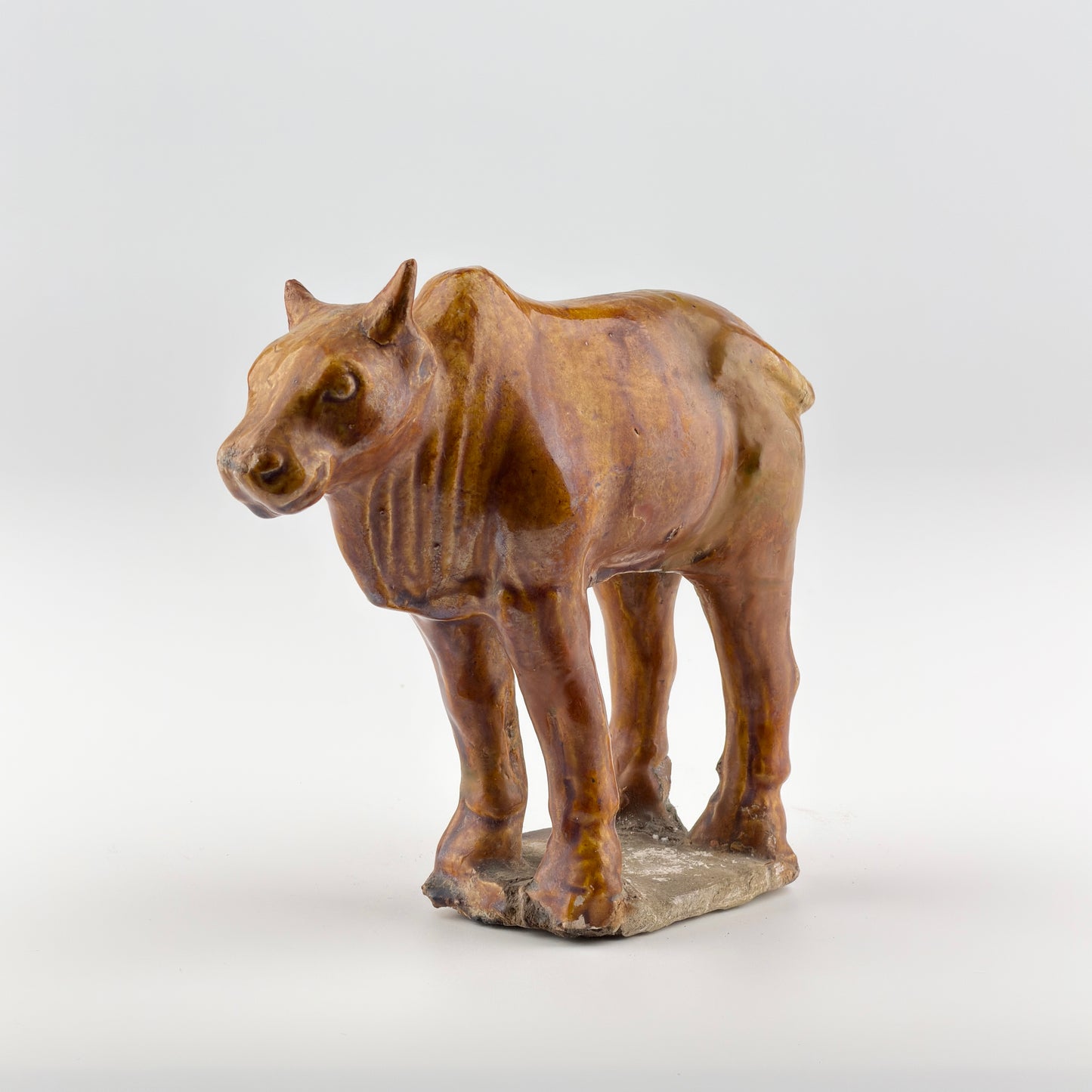 AMBER-GLAZED POTTERY FIGURE OF SACRED BULL, TANG-LIAO DYNASTY (7-12TH CENTURY)