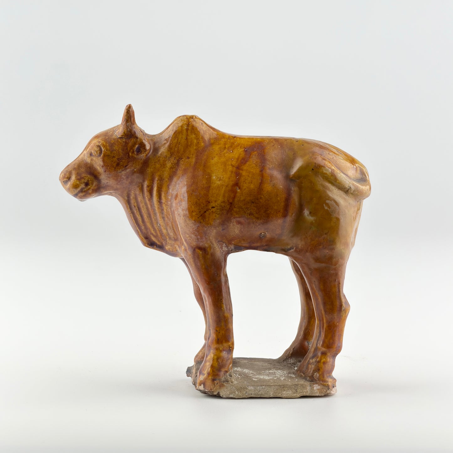 AMBER-GLAZED POTTERY FIGURE OF SACRED BULL, TANG-LIAO DYNASTY (7-12TH CENTURY)