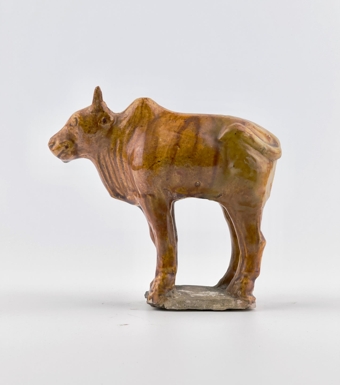 AMBER-GLAZED POTTERY FIGURE OF SACRED BULL, TANG-LIAO DYNASTY (7-12TH CENTURY)