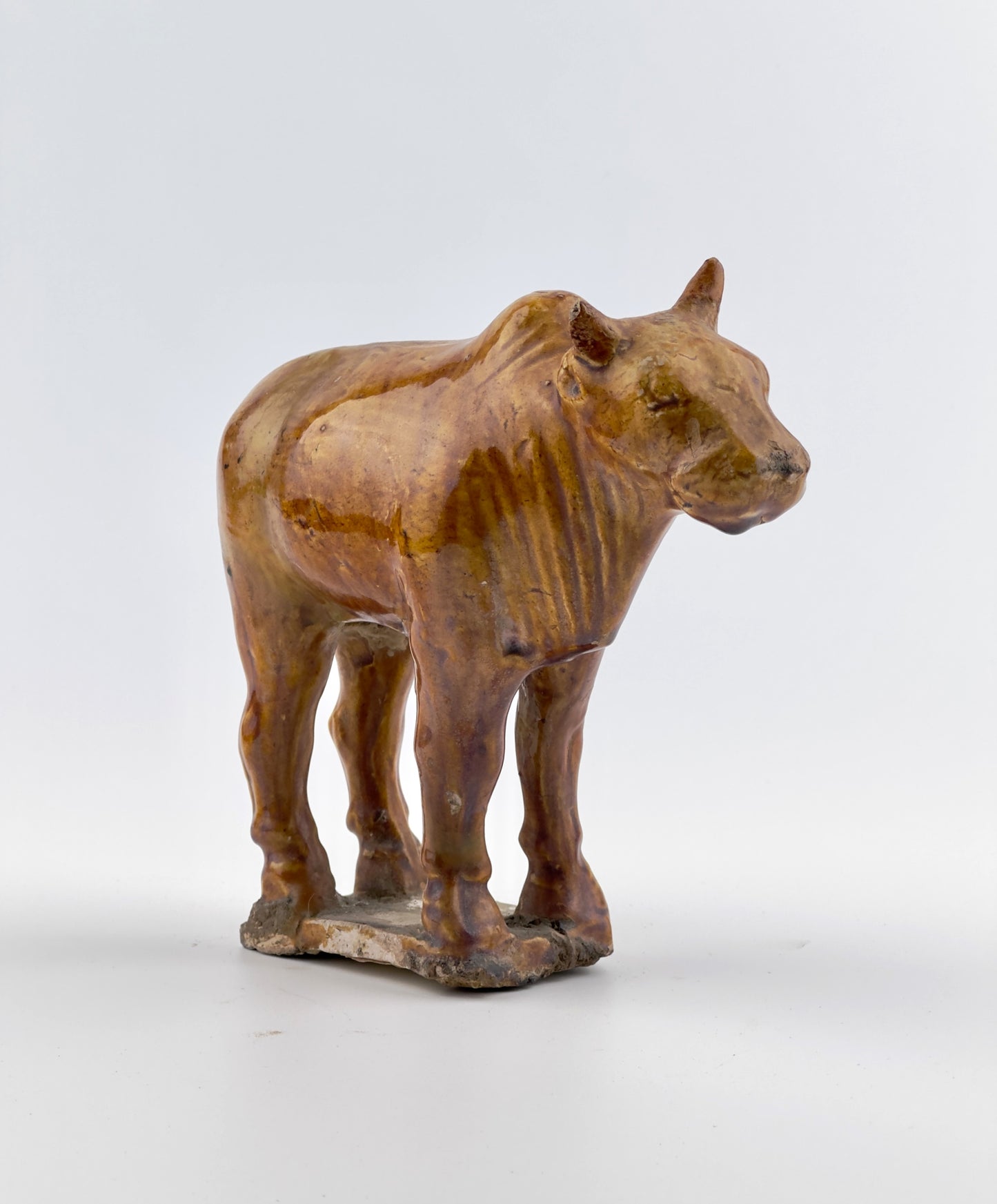 AMBER-GLAZED POTTERY FIGURE OF SACRED BULL, TANG-LIAO DYNASTY (7-12TH CENTURY)