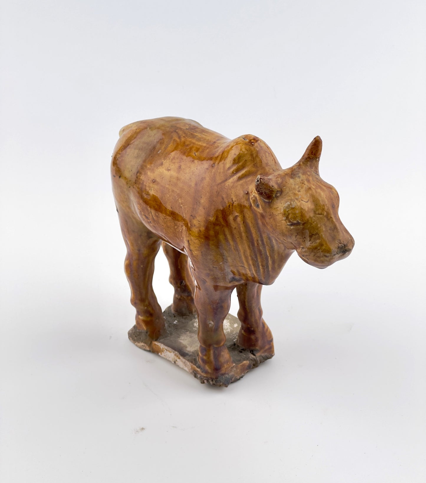 AMBER-GLAZED POTTERY FIGURE OF SACRED BULL, TANG-LIAO DYNASTY (7-12TH CENTURY)