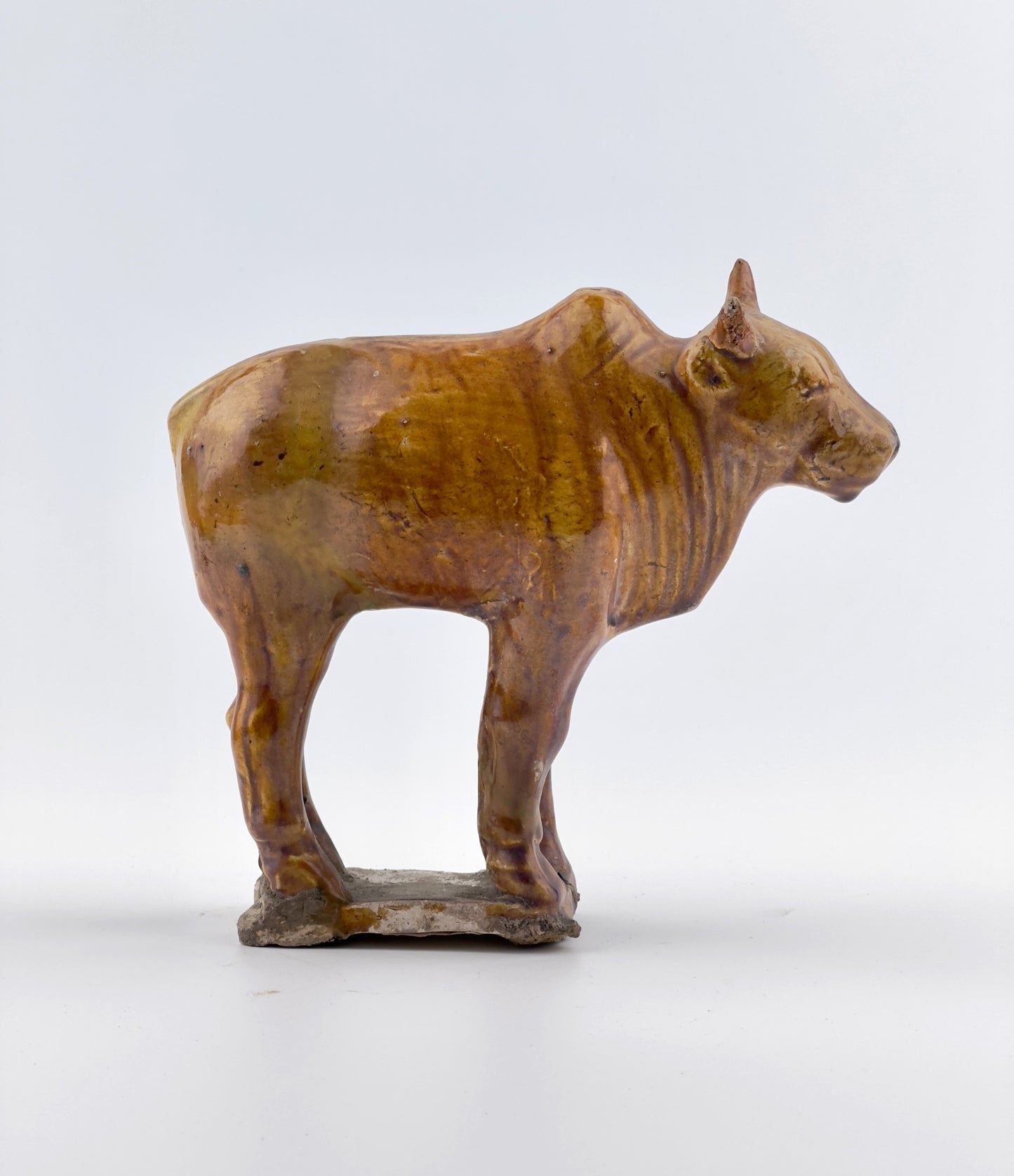 AMBER-GLAZED POTTERY FIGURE OF SACRED BULL, TANG-LIAO DYNASTY (7-12TH CENTURY)