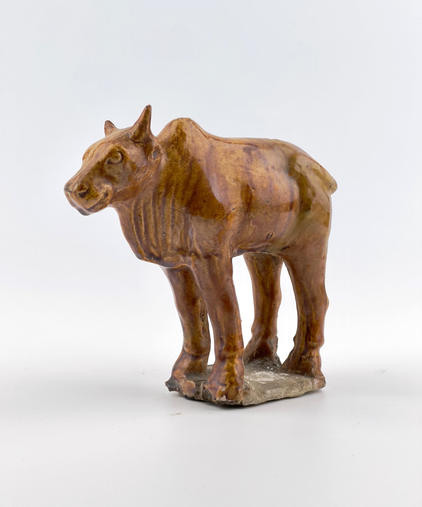 AMBER-GLAZED POTTERY FIGURE OF SACRED BULL, TANG-LIAO DYNASTY (7-12TH CENTURY)