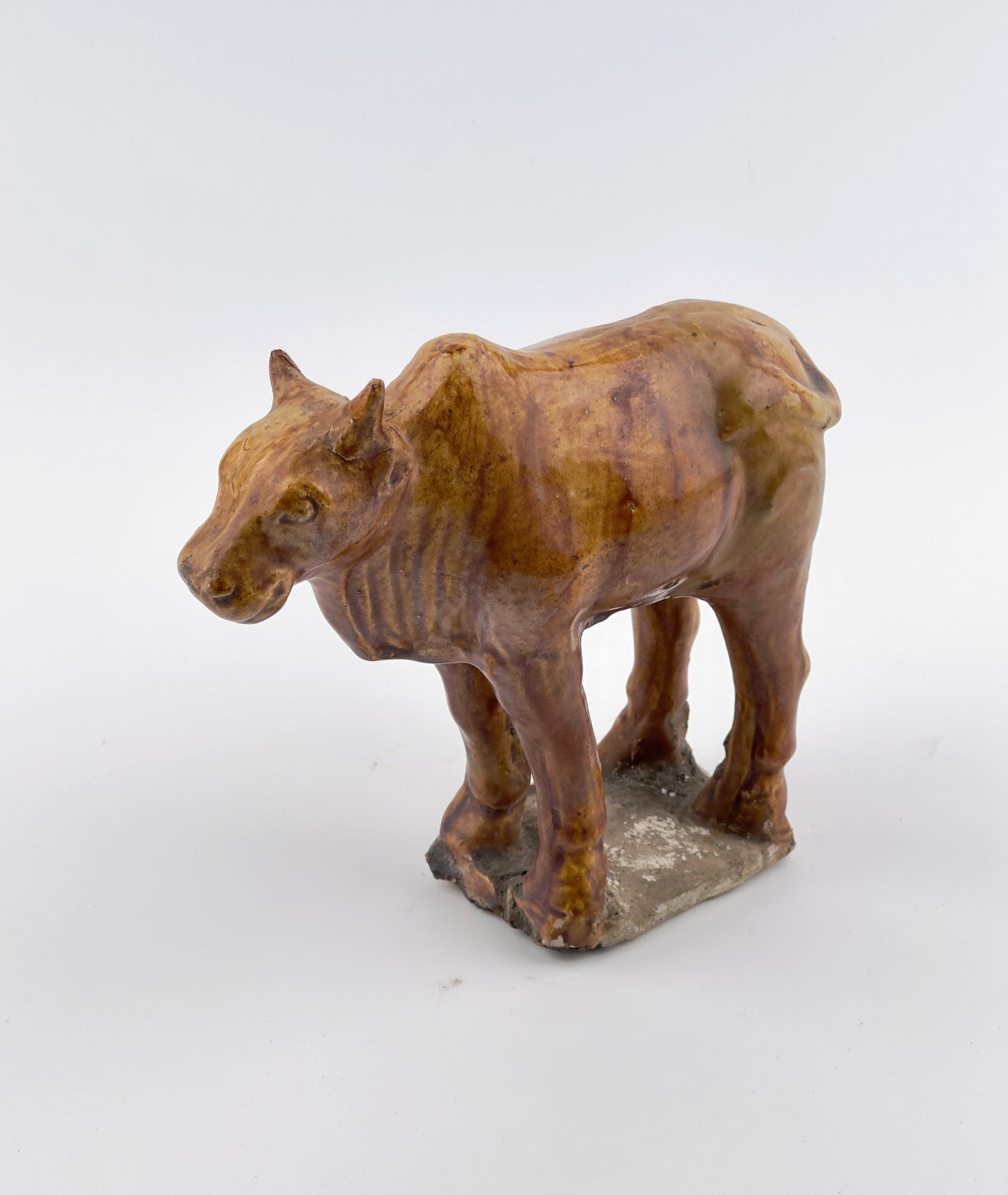 AMBER-GLAZED POTTERY FIGURE OF SACRED BULL, TANG-LIAO DYNASTY (7-12TH CENTURY)