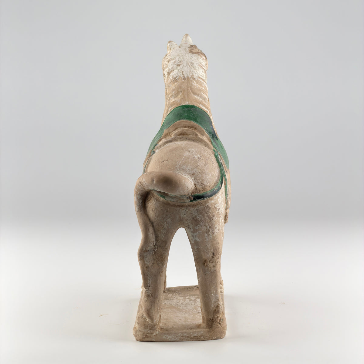 Ming Dynasty pottery horse figure with green-glazed saddle and harness, standing on a rectangular base with aged burial patina.