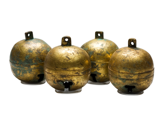 Set of four ancient gilt-bronze bells with cloud-scroll motifs, original gilding traces, and green turquoise patina.