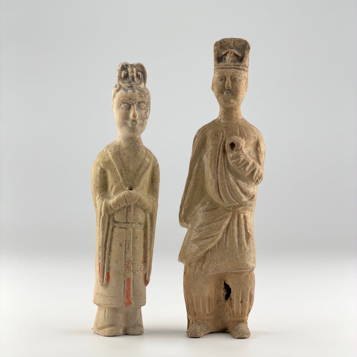Sui-Tang Dynasty pair of straw-glazed pottery court figures with traditional robes, official cap, and red pigment traces.