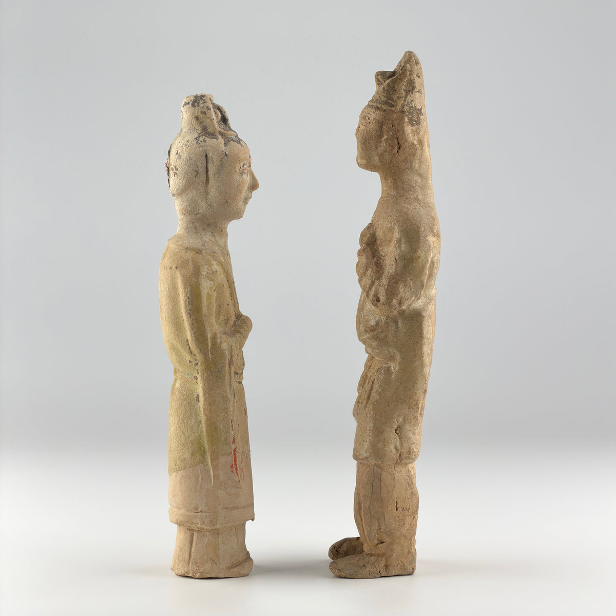 Sui-Tang Dynasty pair of straw-glazed pottery court figures with traditional robes, official cap, and red pigment traces.