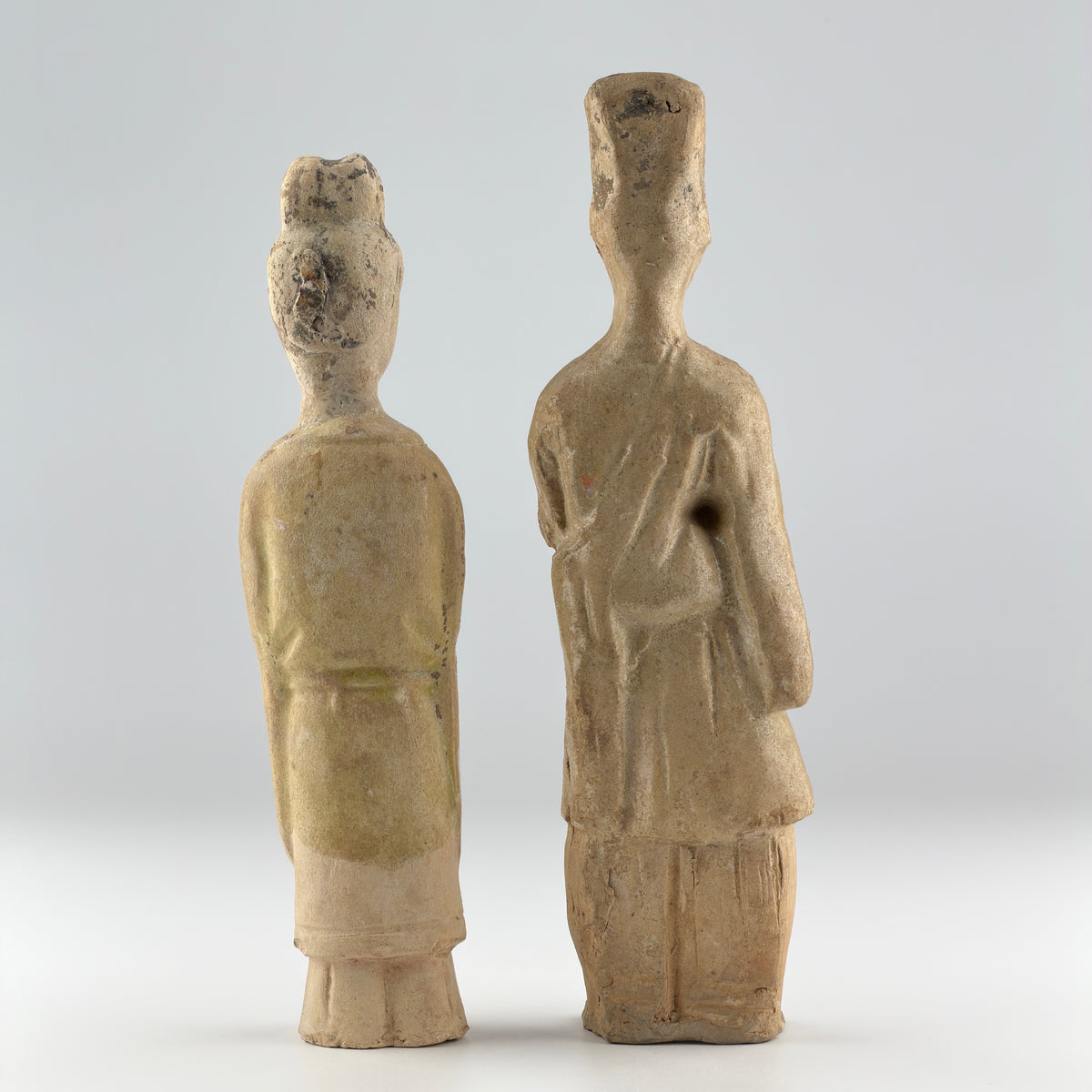 Sui-Tang Dynasty pair of straw-glazed pottery court figures with traditional robes, official cap, and red pigment traces.
