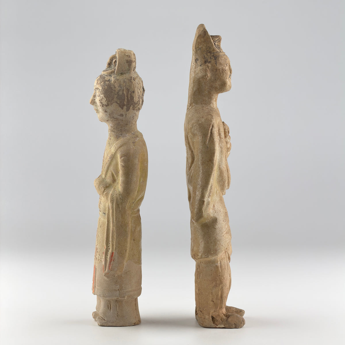Sui-Tang Dynasty pair of straw-glazed pottery court figures with traditional robes, official cap, and red pigment traces.