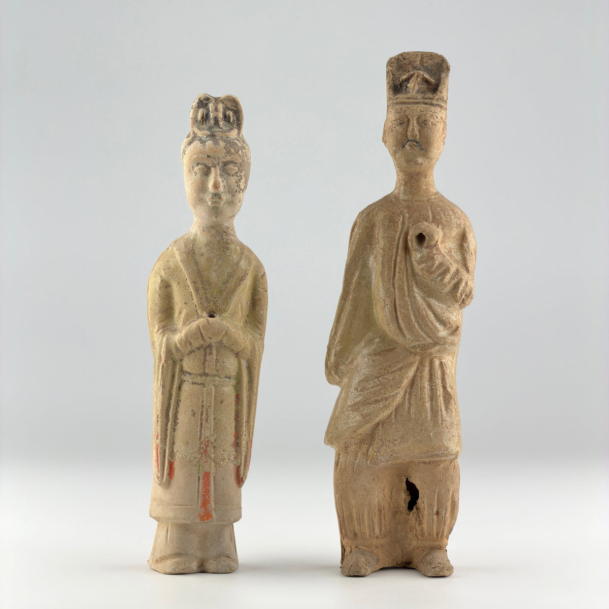 Sui-Tang Dynasty pair of straw-glazed pottery court figures with traditional robes, official cap, and red pigment traces.